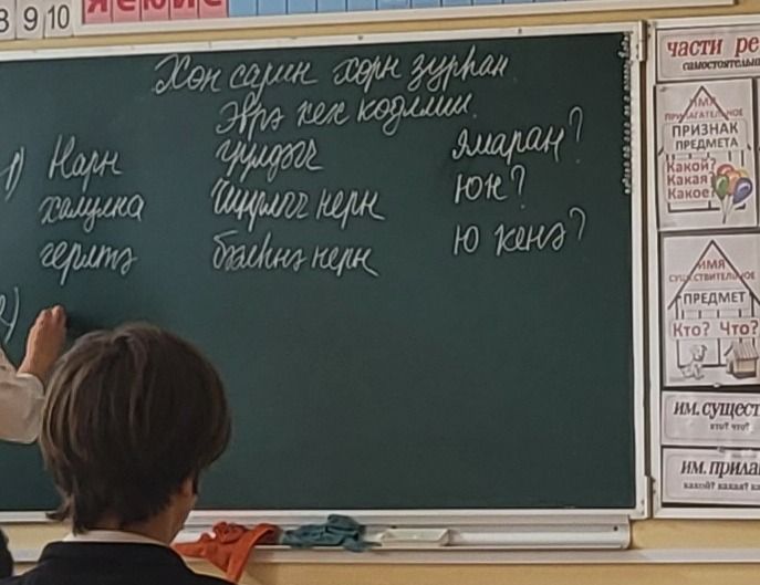 Фото задания: The text on the blackboard appears to be a list of words or phrases in a non-Latin script, possibly Cyrillic or a related…