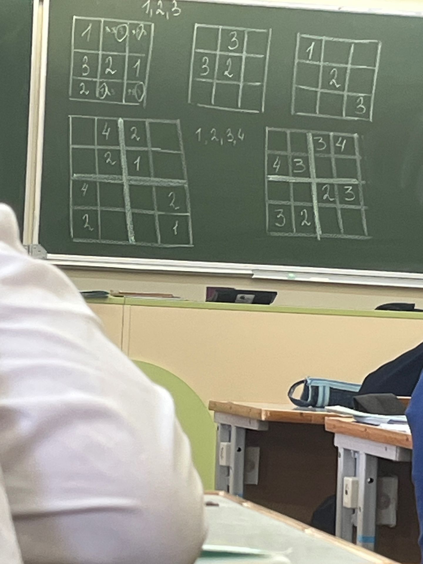 Фото задания: The user wants me to analyze the content of the image, which appears to be a blackboard with Sudoku-like puzzles and some…