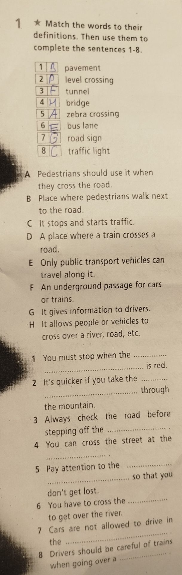 Фото задания: Match the words to their definitions. Then use them to complete the sentences 1–8. Words: 1 pavement, 2 level crossing, 3…
