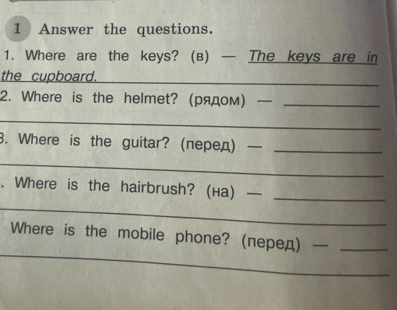 Фото задания: Answer the questions. 1. Where are the keys? (B) — The keys are in the cupboard. 2. Where is the helmet? (рядом) — 3. Where…