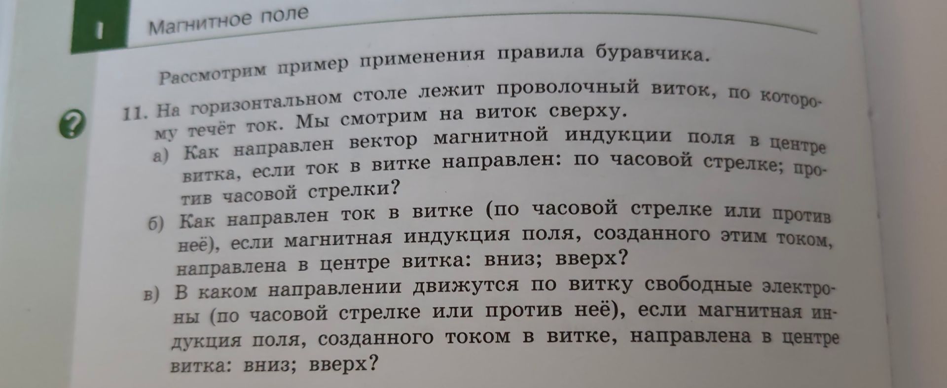 Фото задания: 11. На горизонтальном столе лежит проволочный виток, по которому течёт ток. Мы смотрим на виток сверху. а) Как направлен…