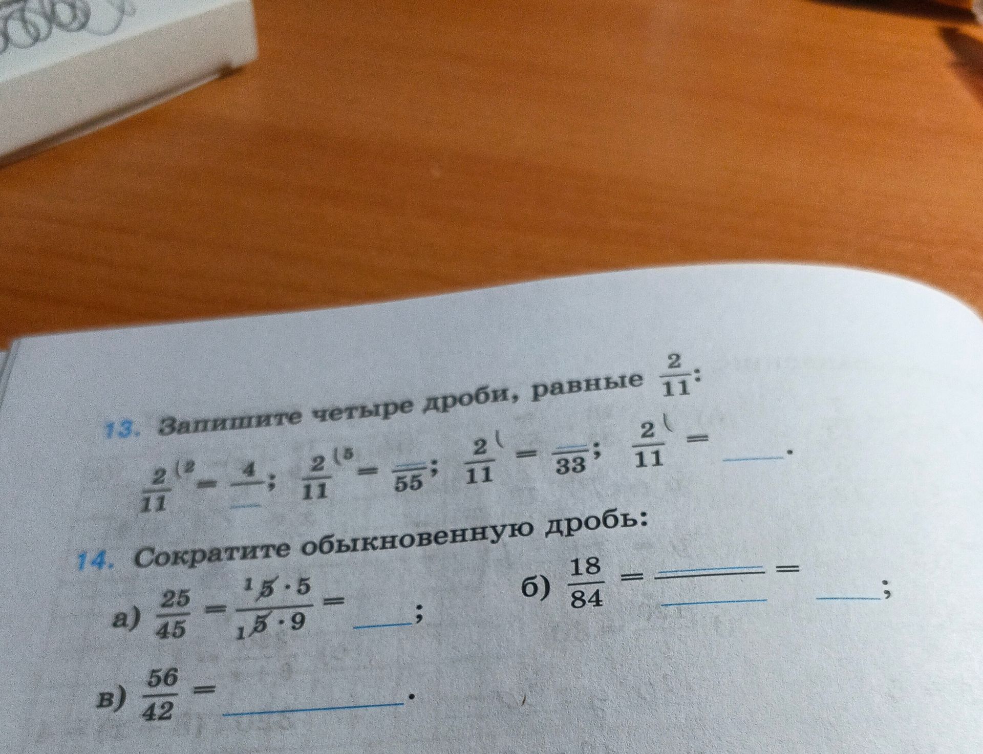 Фото задания: 14. Сократите обыкновенную дробь: а) \(\frac{25}{45}=\frac{15\cdot5}{15\cdot9}=\_\); б) \(\frac{18}{84}=\_\frac{\_}{\_}\); в)…