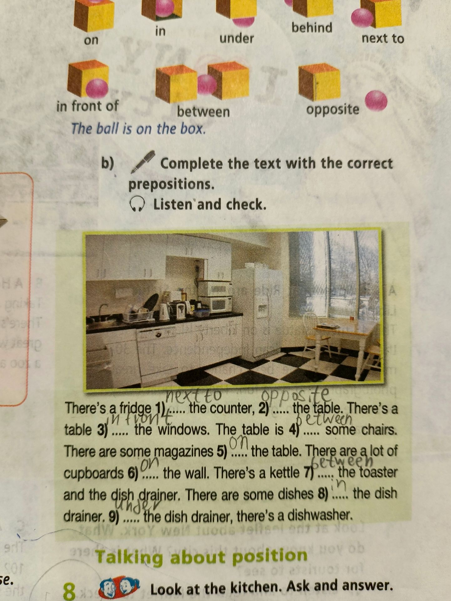 Фото задания: b) Complete the text with the correct prepositions. Listen and check. There’s a fridge 1) ____ the counter, 2) ____ the…