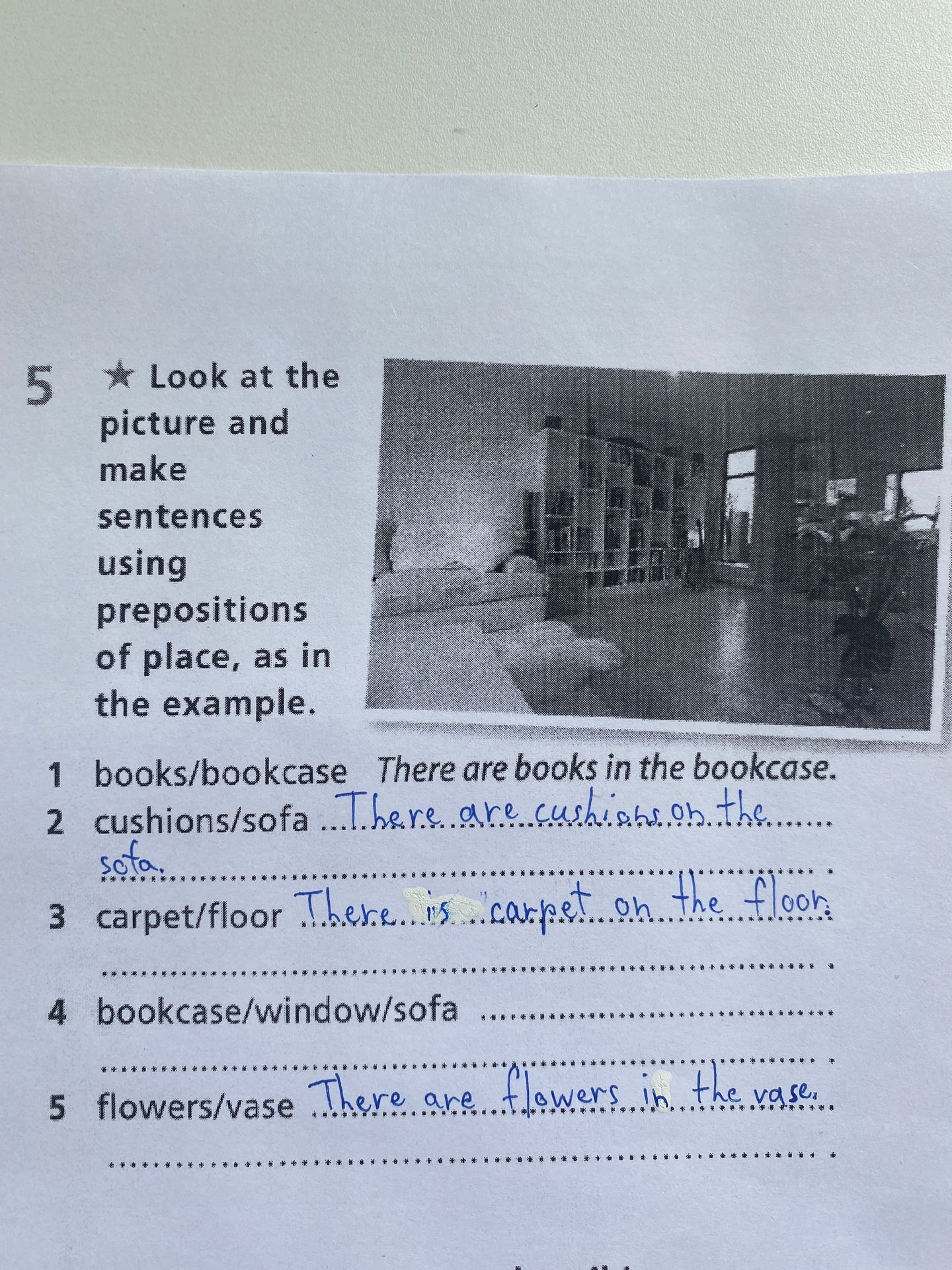 Фото задания: 5. Look at the picture and make sentences using prepositions of place, as in the example. 1. books/bookcase — There are books…
