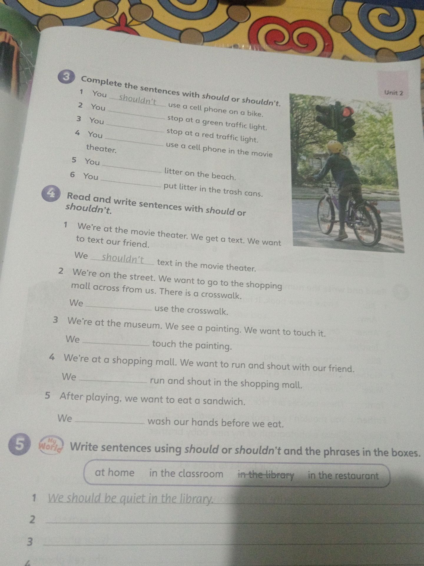 Фото задания: 4. Read and write sentences with should or shouldn’t. 1) We’re at the movie theater. We get a text. We want to text our…
