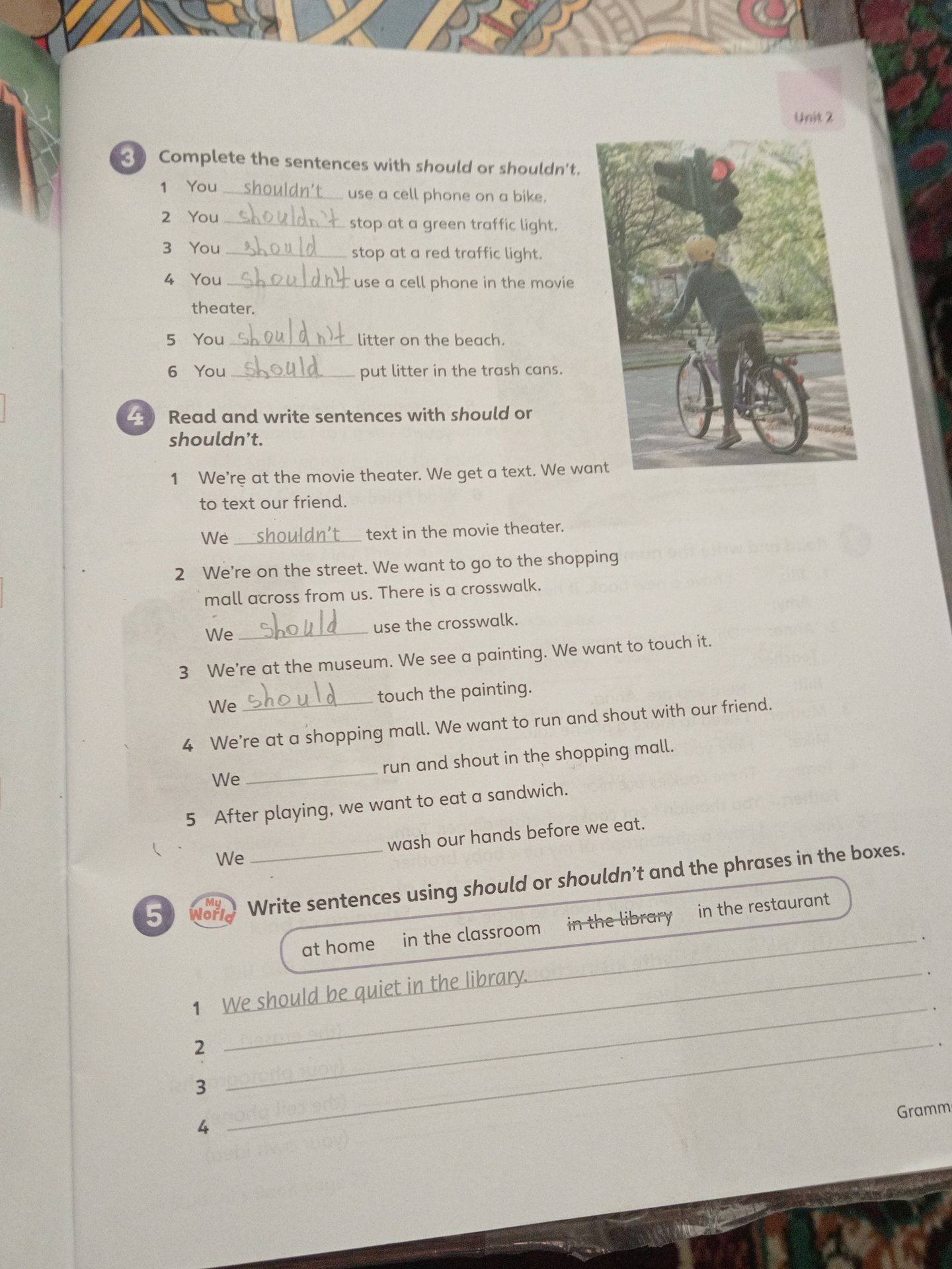 Фото задания: 3. Complete the sentences with should or shouldn’t. 1) You ___ use a cell phone on a bike. 2) You ___ stop at a green traffic…
