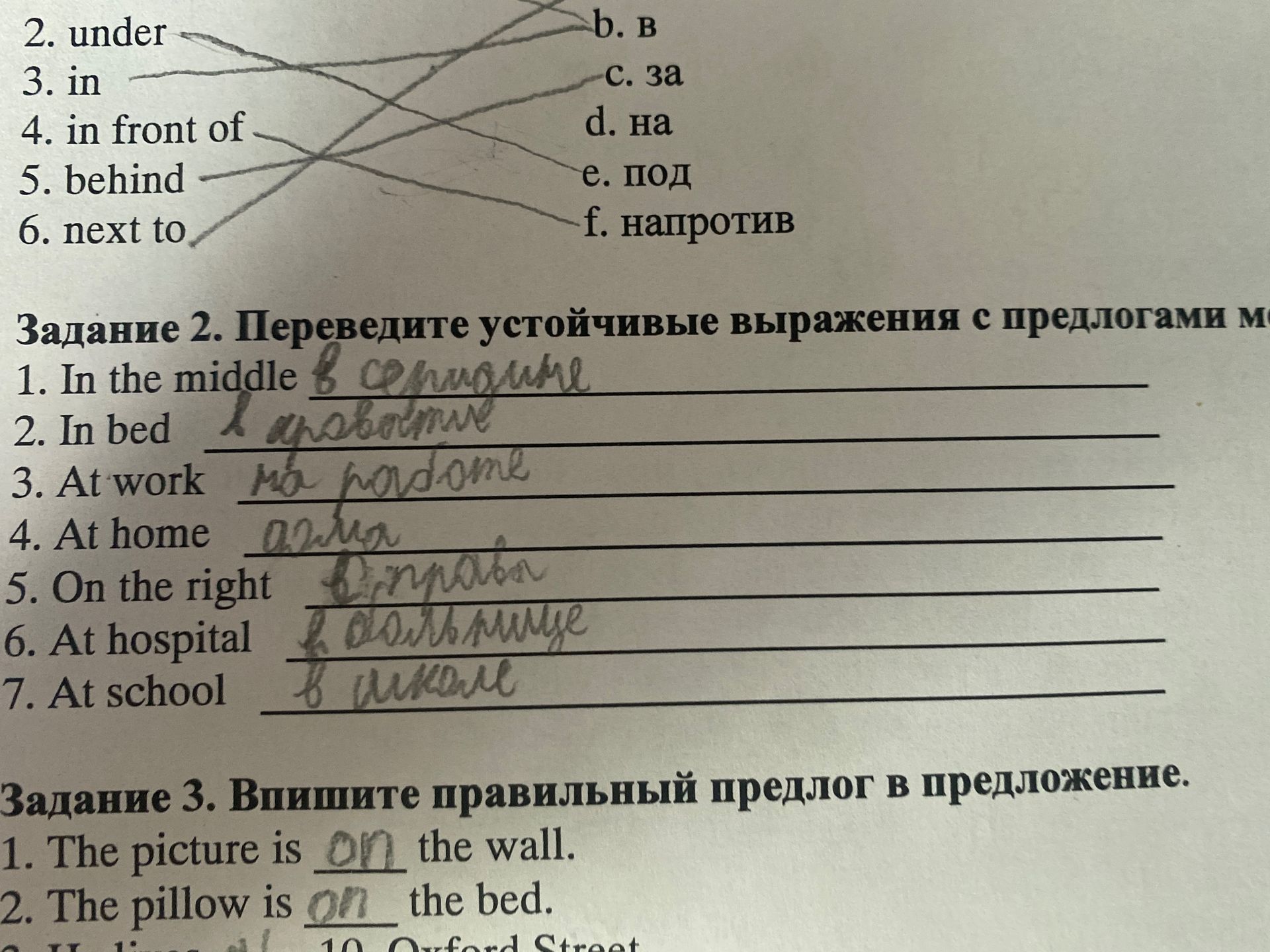 Фото задания: 2. under; 3. in; 4. in front of; 5. behind; 6. next to. Соотнесите выражения с русскими вариантами: b. в; c. за; d. на; e.…